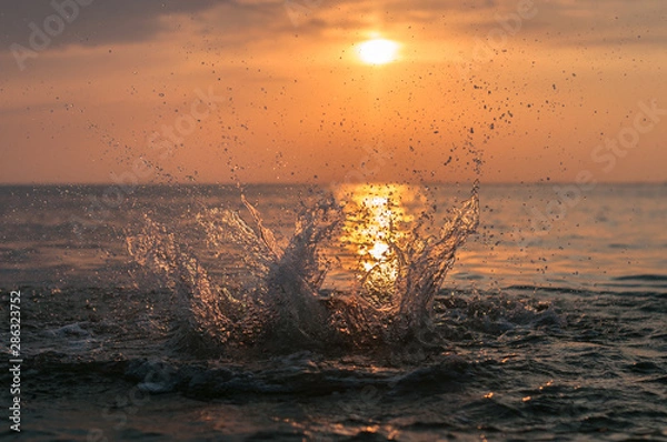 Obraz A water splash with a sunset on the background