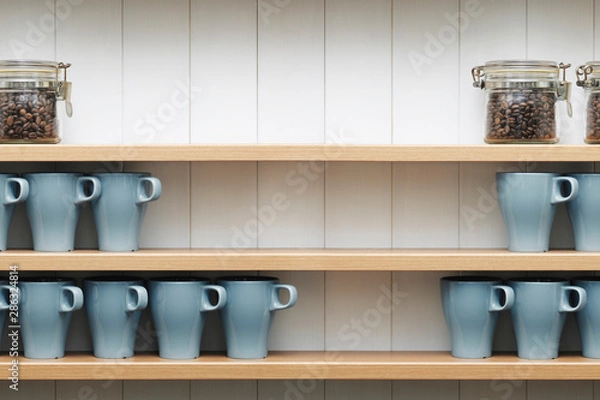 Obraz  ceramic cups on the shelves in front of white wall.
