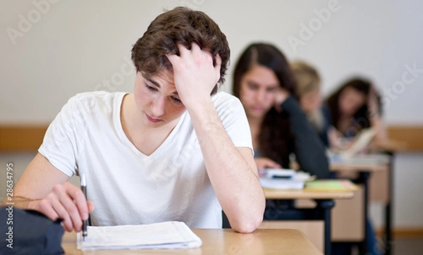 Fototapeta Student working on homework in classroom