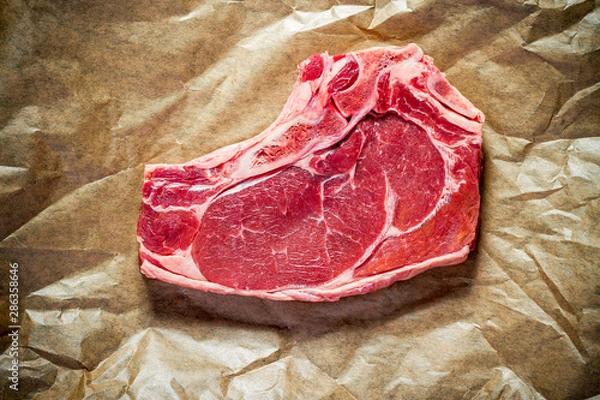 Fototapeta Fresh, huge and appetizing club steak on brown paper