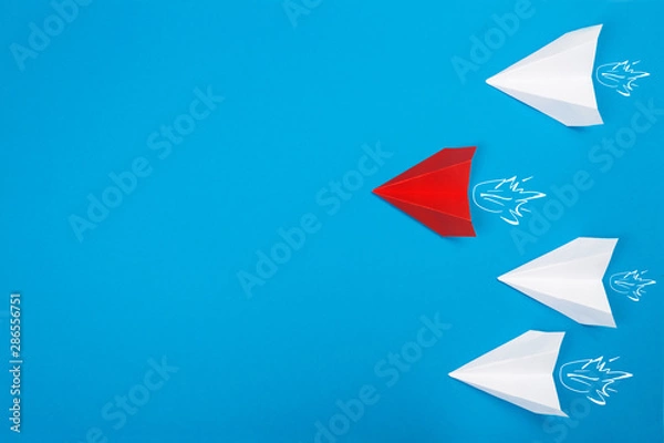 Obraz Group of white paper plane in one direction and one red paper plane pointing in different way on blue background. Business for innovative