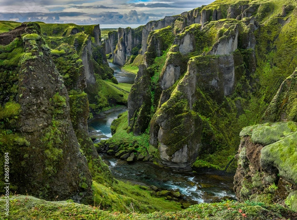 Fototapeta Fjaðrárgljúfur Canyon in southern Iceland. The canyon was carved through the lava and palagonite by progressive erosion by  the Fjaðrá River, fed by meltwater from glaciers over millennia.