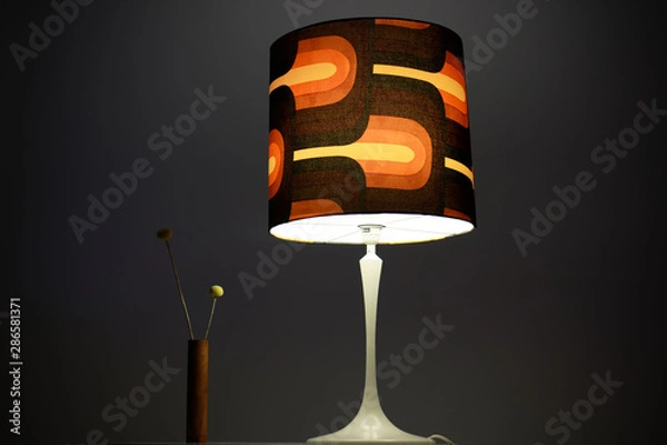 Obraz a vintage midcentury lamp from the 60s with a large brown lampshade standing on a cocktail table in the living room of a  loft luminous brown white pedestal lit bedside lamp  interior design warm HQ