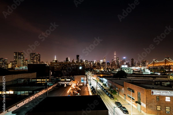 Fototapeta Long island City, New York City/ USA - 08 21 2017: View to the Queensboro Bridge in LIC NYC Big Apple at an bright night sky with skyscrapers and the amazing skyline of Manhattan in background