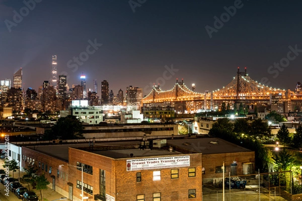 Fototapeta Long island City, New York City/ USA - 08 21 2017: View to the Queensboro Bridge in LIC NYC Big Apple at an bright night sky with skyscrapers and the amazing skyline of Manhattan in background