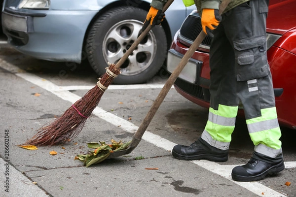 Fototapeta Garbage man brooming the leaves