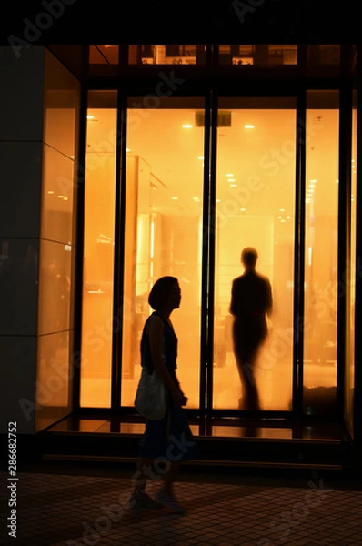 Obraz 男性と女性のシルエットがオレンジ色のウィンドウで交叉する