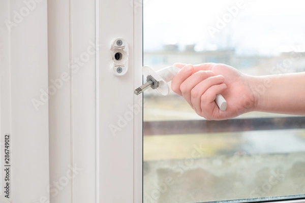 Fototapeta A man holds in his hand a broken doorknob. The door is closed due to negligence and the use of high power or due to defective parts
