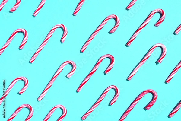 Fototapeta Pattern of Christmas candy cane on blue background. Top view. Flat lay. Creative minimal concept. Greeting card on Christmas and New Year. Art composition.