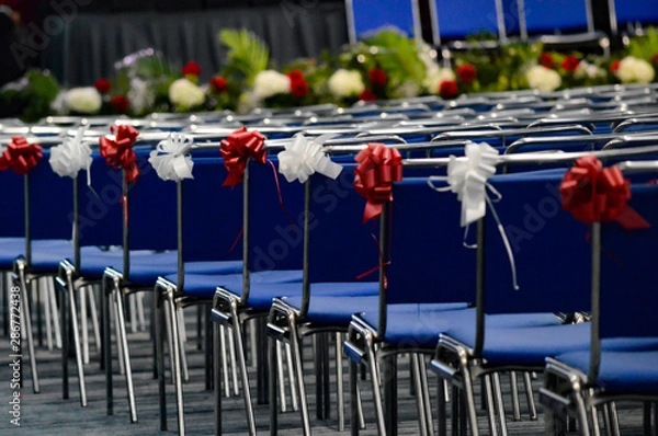 Obraz Rows of seats with red and white ribbons waiting for graduating students