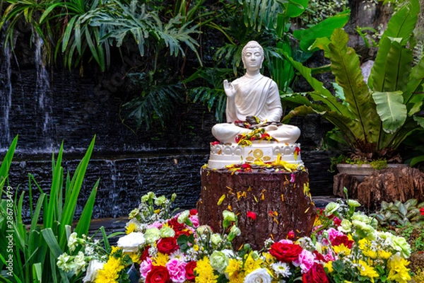Obraz Small home garden private fountain pond with meditating Buddha statue between trees and bushes. Private zen garden concept. Songkran Thai famous festical concept. 