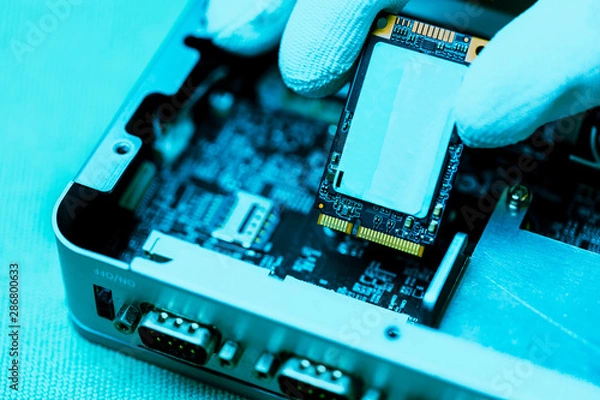 Fototapeta Hand holding tiny electronic circuit board inserting to the socket, abstract technology background, engineering and technical experimental kit concept.