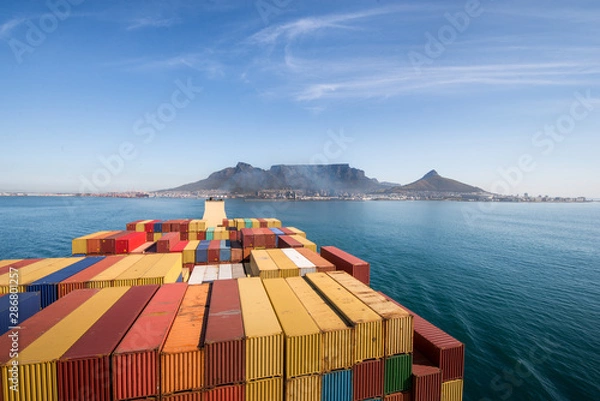 Obraz Large stacked container ship leaving the port of Cape Town with Table mountain and the city in the background, South Africa.