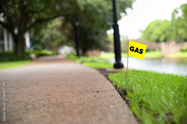 Fototapeta Gas line stake flag buried underground utility beside a footpath