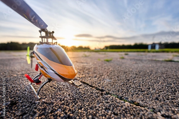 Obraz A RC helicopter standing on the ground during sunset on a beautiful summer day