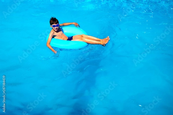 Fototapeta top view boy in the pool on an rubber ring, healthy lifestyle concept.