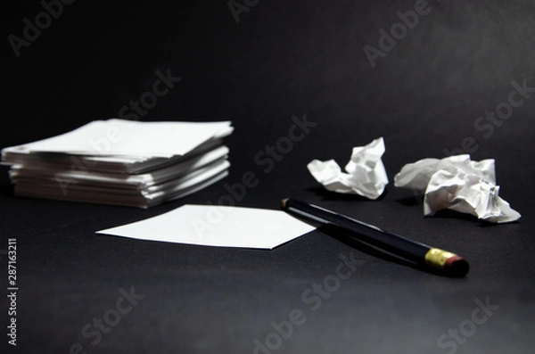 Fototapeta White square stickers crumpled pieces of paper of the same size on a black background with a simple pencil