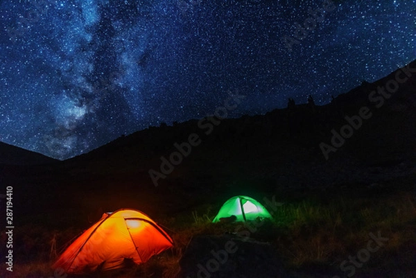 Fototapeta Space starry nights with a bright Milky Way on the backdrop of tourists with tents.