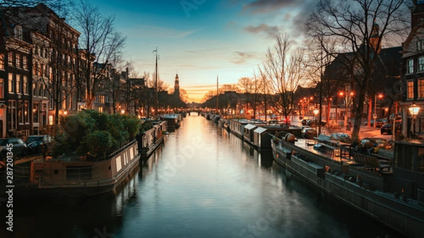 Fototapeta Houseboats in the Prinsengracht in the old center of Amsterdam with the spire of the Westertoren in the background during sunset