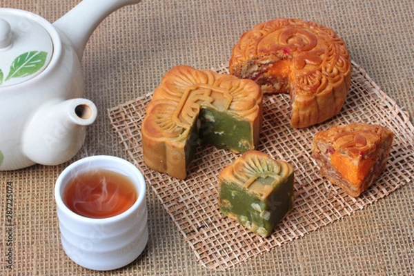 Obraz Round mooncake.8 grains and salted eggs and squred mooncake filled red beans, stirred in green tea and chopped macadamia nuts served  with tea and teapot.