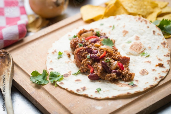 Obraz tortilla Chili con carne with corn chips on a wooden cutting board