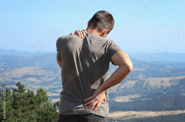 Fototapeta Back pain relief. Man hiker with back pain