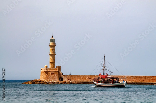 Fototapeta Boat leaving the harour of Chania, Crete with the unrecognizable people on the  harbour wall by the lighthouse