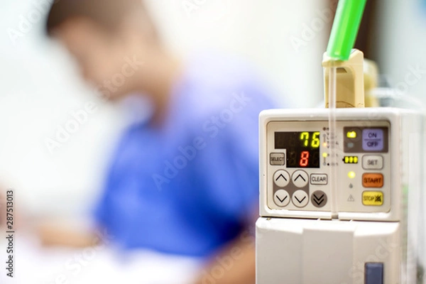 Fototapeta Selective focus to Infusion pumps with blurry patient play smart phone in hospital. The concept of working anytime. - Image