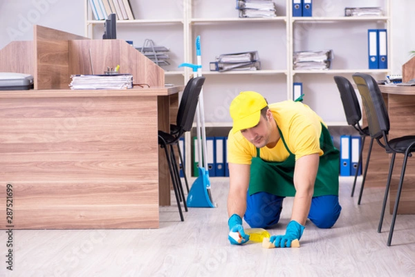 Obraz Young male contractor cleaning the office