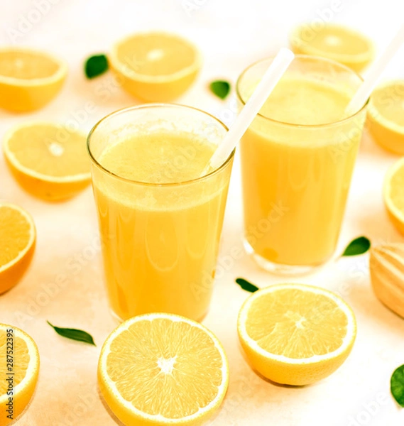 Fototapeta freshly squeezed orange juice in glasses on the kitchen table with slices of oranges, concept of diet and healthy lifestyle