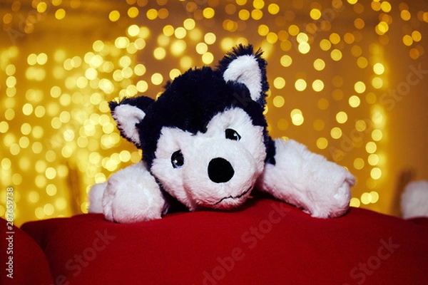 Obraz Little toy dog on the background of yellow New Year lights