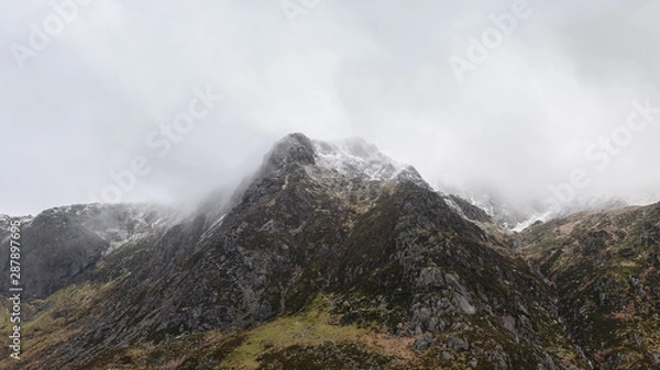 Fototapeta Stunning moody dramatic Winter landscape image of snowcapped Y Garn mountain in Snowdonia