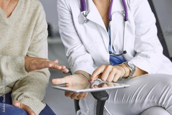 Fototapeta female doctor talking to a patient on a tablet