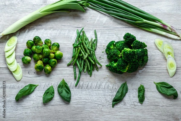 Fototapeta Fresh green food on a light table. Avocados cucumbers cabbage apples beans kiwi onions broccoli. The concept of healthy food, detox vegetarianism. Copy space flat lay.