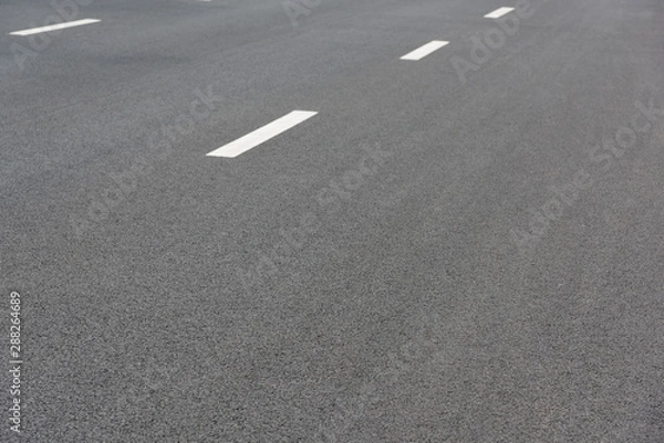 Fototapeta Low angle perspective view of two white paint dashed lines on asphalt road