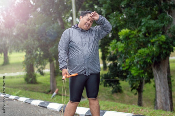 Fototapeta fat obese man doing exercises with jumping rope overweight guy training workout weight loss