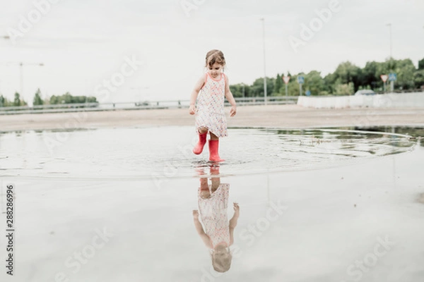 Obraz Little girl playing in a puddle, happy. stock photo