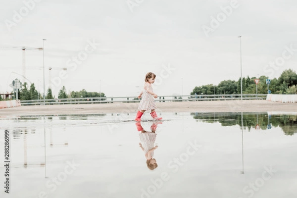 Obraz Little girl playing in a puddle, happy. stock photo
