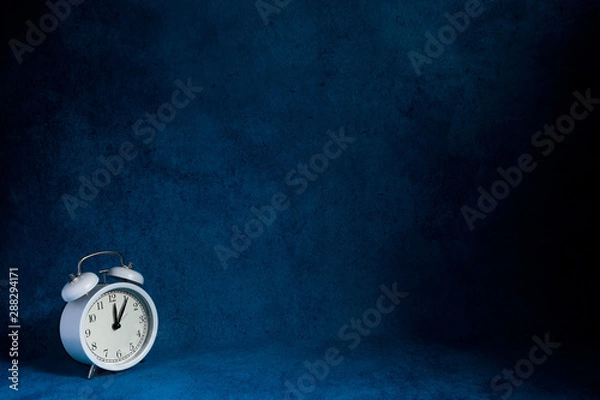 Obraz white vintage alarm clock on abstrac blue background