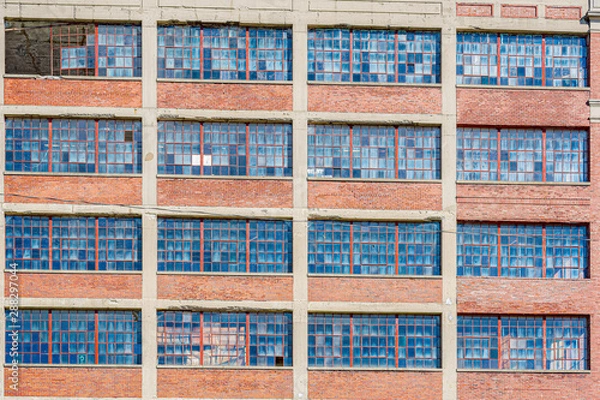 Fototapeta Abandoned factory's multiple floors of broken and rusted windows