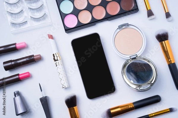 Fototapeta Creative arrangement of cosmetics on white background. Smartphone with blank display in the middle. 
