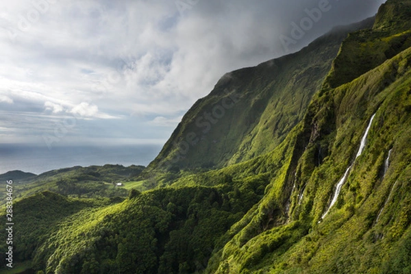 Fototapeta aerial landscape image of sunset sunrise over Poço Ribeira do Ferreiro waterfalls with its remarkable amazing tropical like green vegetation and forests at the Ilha das Flores island on the Azores
