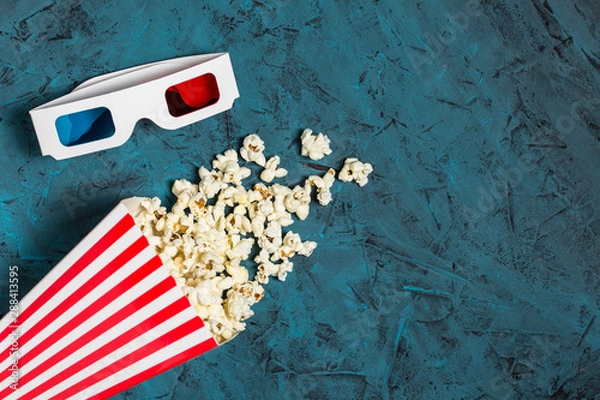 Obraz Popcorn bucket and 3D glasses with copy space on blue textured background. Top view. Flat lay