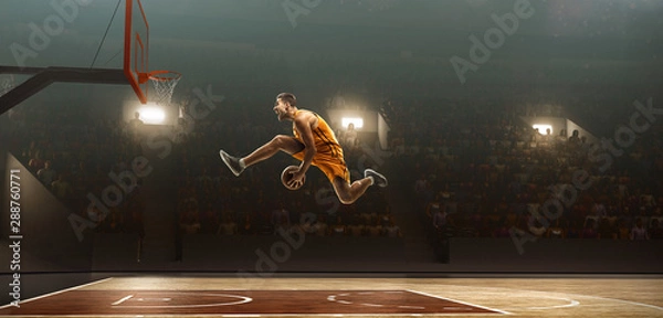 Obraz Professional basketball player on sports arena in action with the ball. Slam dunk