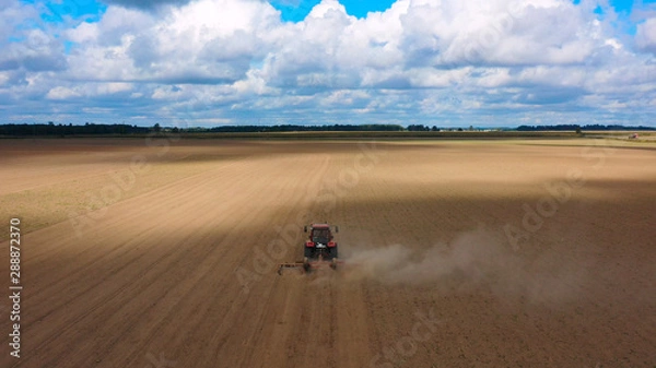Fototapeta Aerial view drone of harvest field with tractor mows dry grass. Autumn yellow field with a haystack after harvest top view. Harves. Ting in the fields. Stock up
