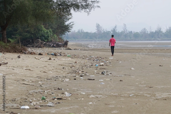 Fototapeta Lok Kawi, Kota Kinabalu, Sabah, Malaysia - September 08, 2019:  Unidentified boy is running on a polluted beach. The beach is full garbage that was washed up from the ocean to the shore. 