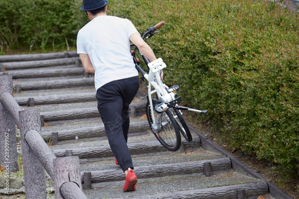 Fototapeta 折り畳み自転車を持ち運ぶ男性