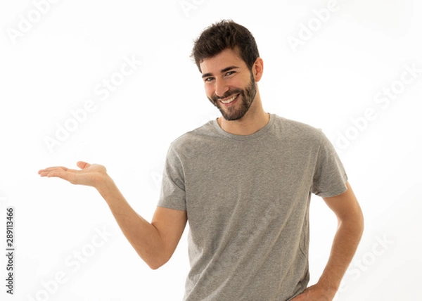 Fototapeta Charming smiling young man pointing finger at empty copy space for advertisement