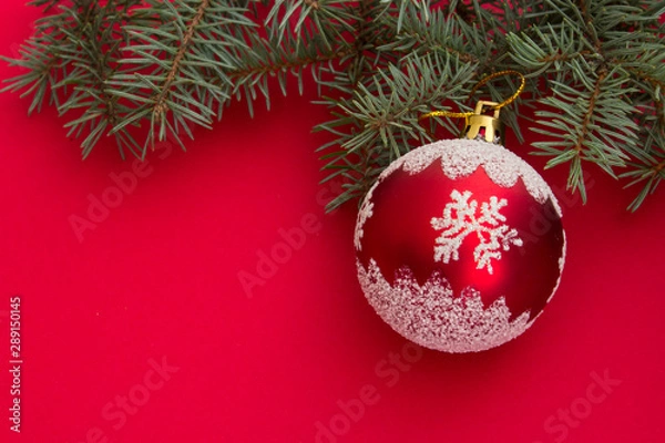 Fototapeta Christmas and New Year background. Colorful christmas composition with xmas tree branches and christmas balls. Christmas tree toy on a red background. Place for text.
