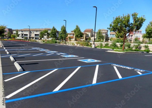 Fototapeta Freshly resurfaced and repainted handicap parking space in a parking lot. The number of handicap spaces increases with the size of the lot, requiring roughly one handicapped spot per 25 spaces.